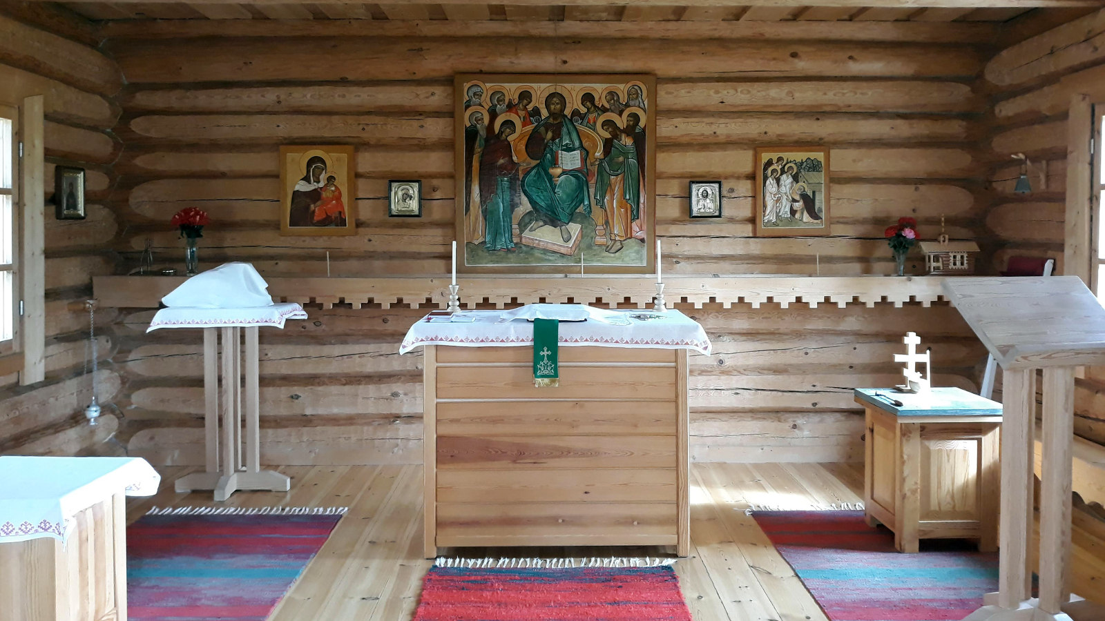 Kuvassa on Kaavin tsasounan sisätila, jossa on hirsisessä rakennuksessa  puukalusteet sekä puinen alttari keskellä.  Seinällä on ikoneita ja suurin keskellä.