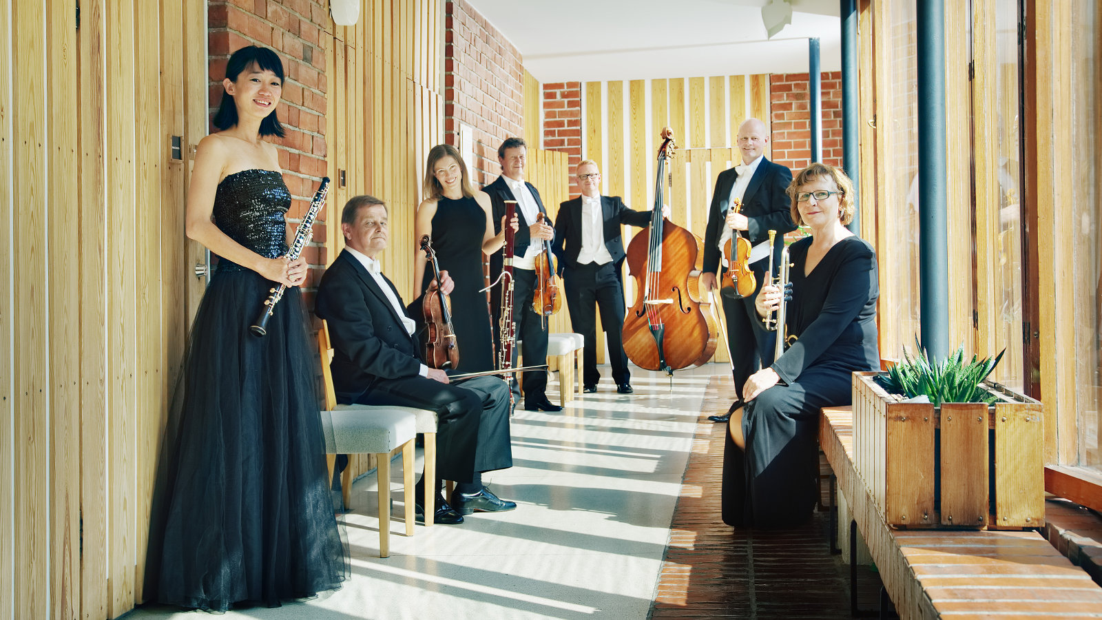 Kuvassa on Jyväskylä Sinfonia käytävässä ja orkesterin jäsenet seisovat.  Kaikilla on esiintymisasut päällä.  