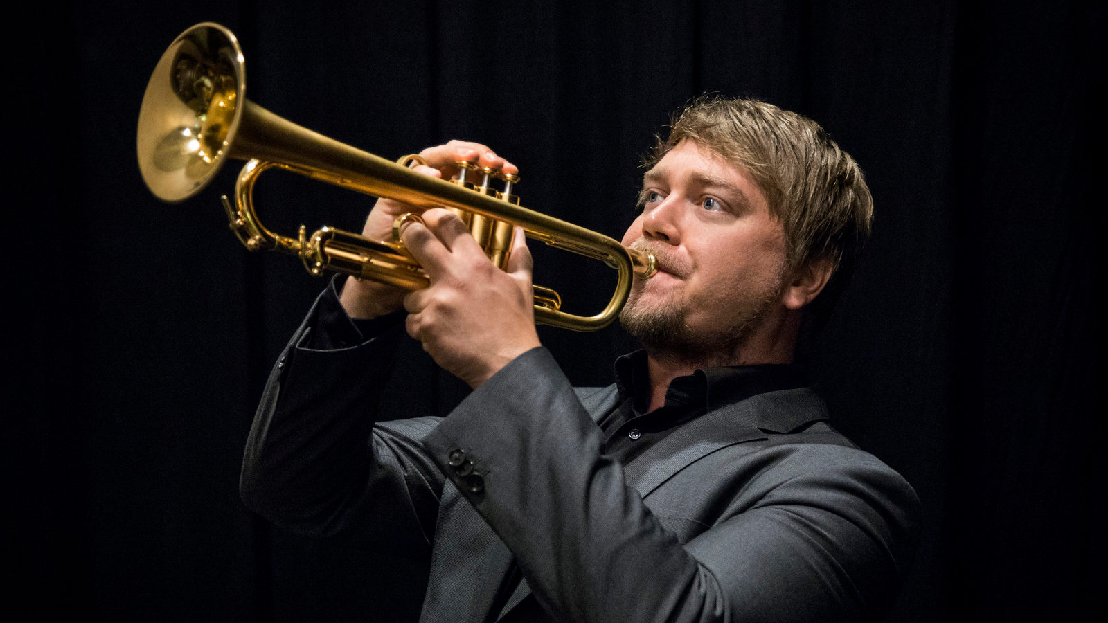 Kuvassa on Tero Lindberg soittamassa trumpettia.  Kuva on yläviistoon ja puolivartalokuva.