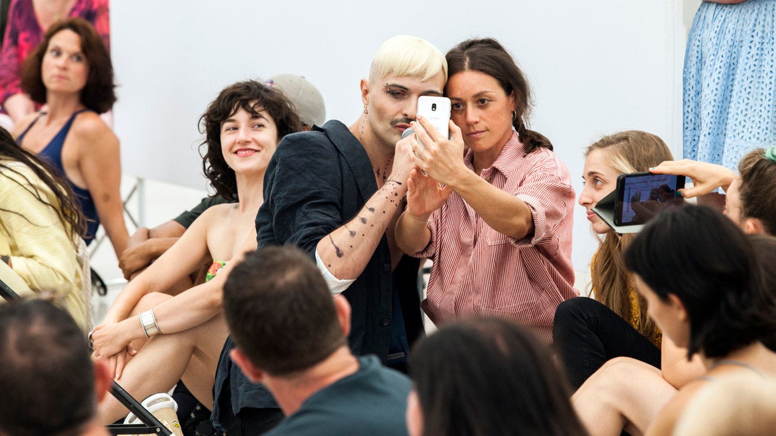 Kuvassa on Ivo Dimchevin ryhmä ja keskellä on kaksi tanssijaa, jotka ottavat selfieta. Muut katselevat.