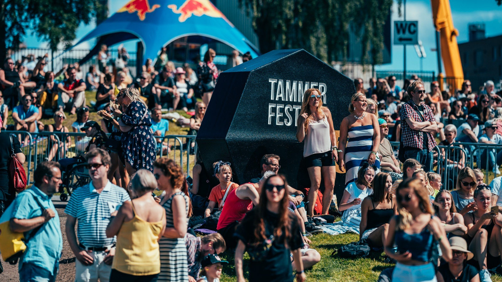 Kuvassa on Tammerfestin avajaisten yleisöä kesäisen aurinkoisessa säässä nauttimassa nurmikolla.