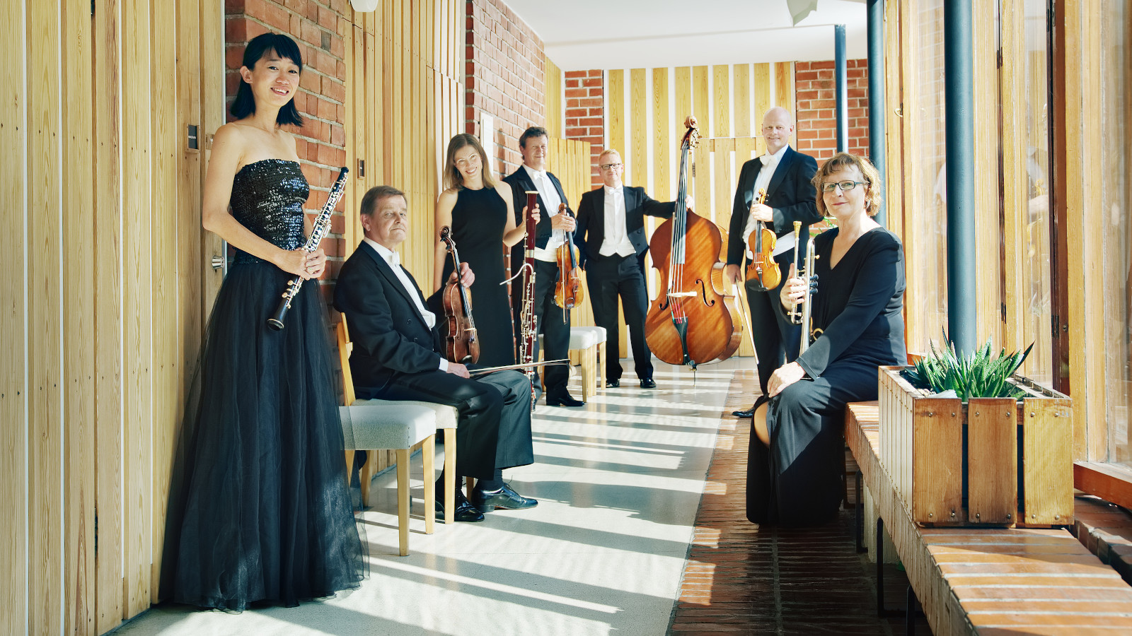 Kuvassa on Jyväskylä Sinfonia käytävätilassa ja soittajat ovat molemmin puolin käytävää rivissä.