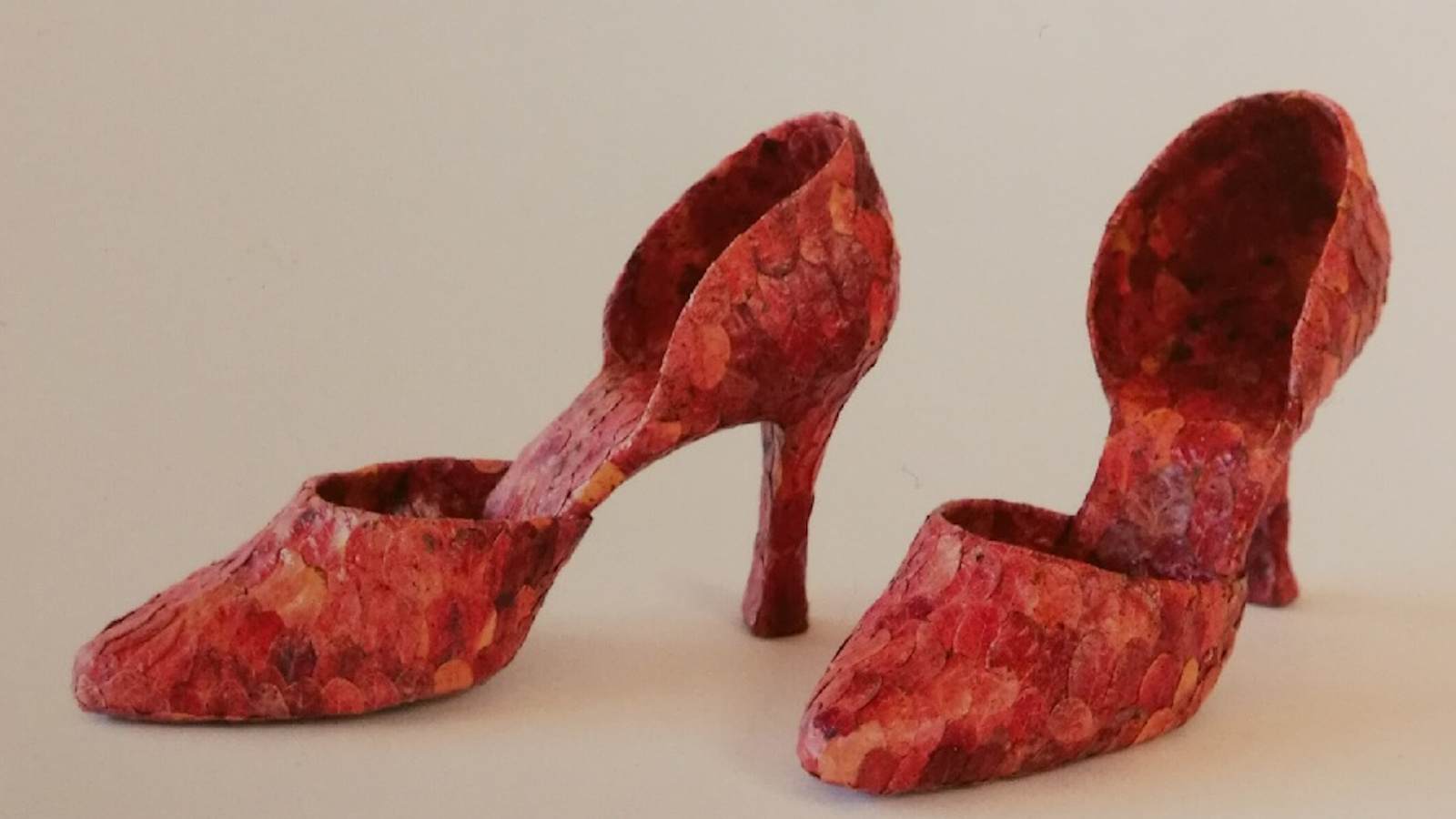 Kuvassa on punaiset kengät, jotka on tehty puolukanlehdistä. Kengissä on korot ja kapeat kärjet.