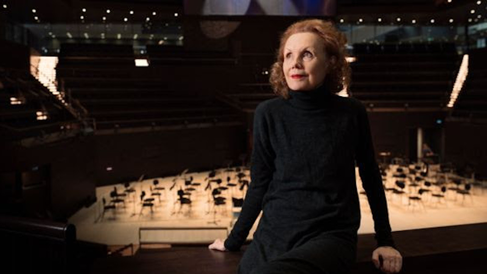 Kuvassa on Kaija Saariaho Musiikkitalon konserttisali takanaan.