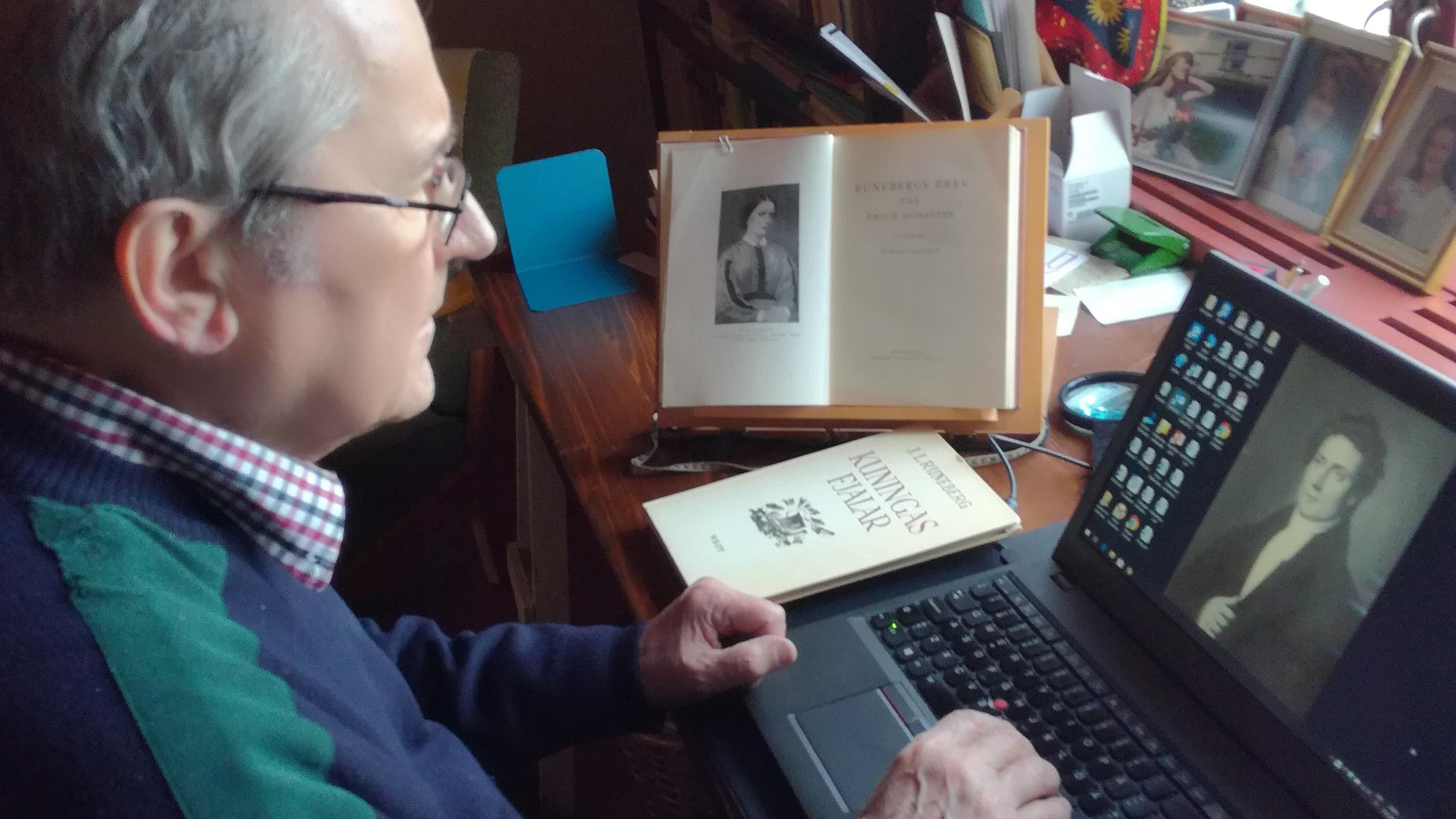 Kuvassa on Panu Rajala tietokoneen ääressä kirjoittamassa. Päätteeltä näkyy J.L. Runebergin kuva.