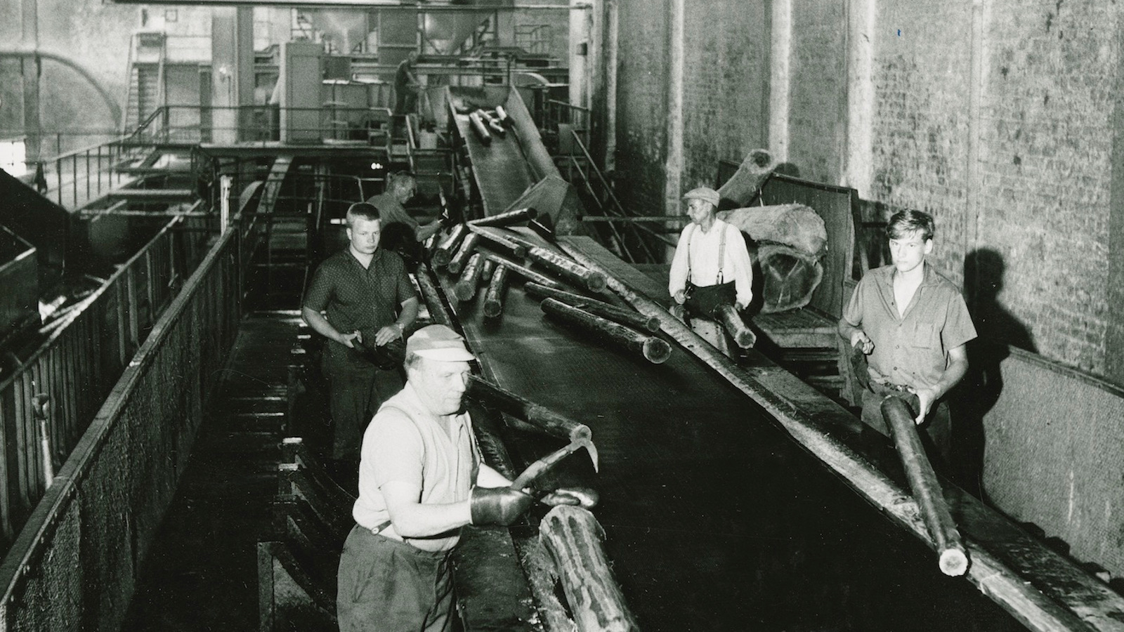 Kuvassa on Serlachiuksen tehtaiden kuorimohalli ja siellä miehiä töissä.  Kuva on musta-valkoinen.