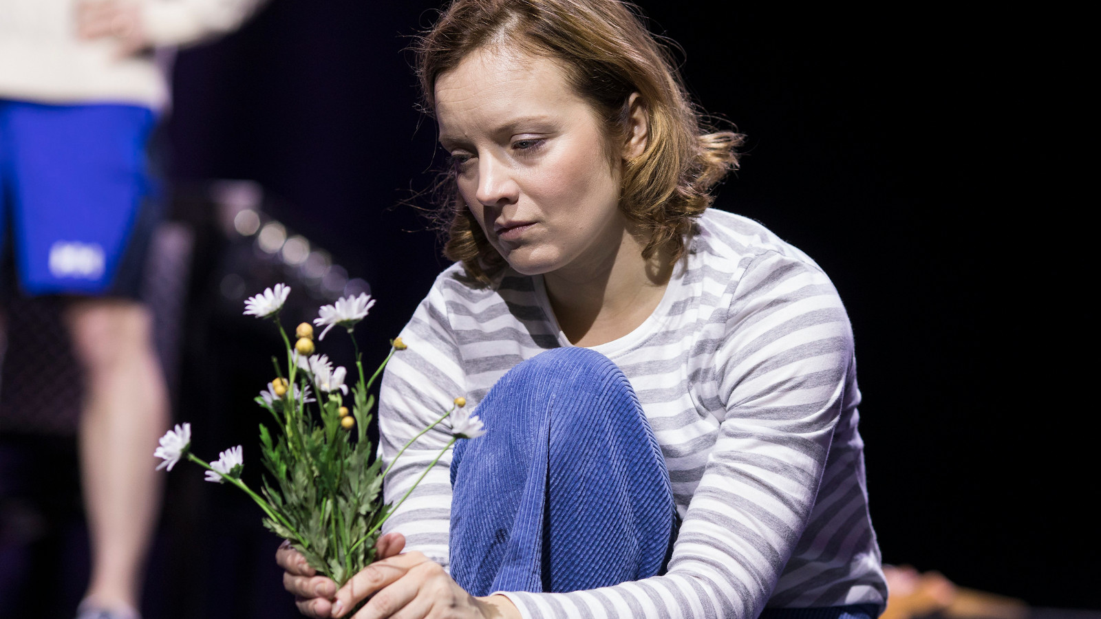 Kuvassa on Eleena Leeve, joka pitää kädessään valkoisia kukkia. 