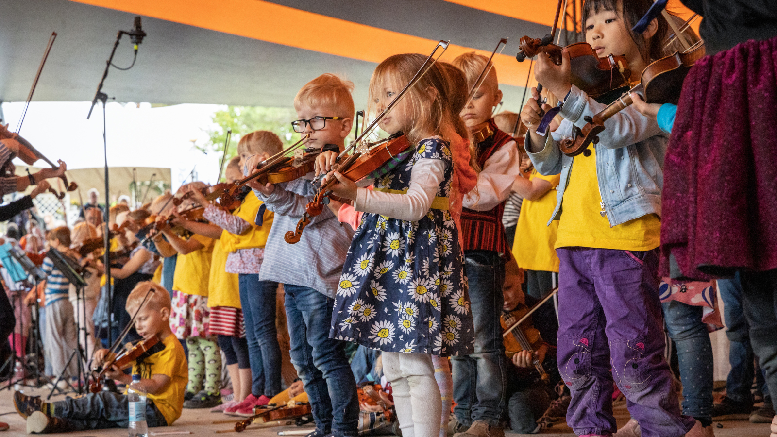 Kuvassa on pikkutyttöjä soittamassa viulua esiintymislavalla Kaustisilla.  Jokaisella on omat vaatteet esiintymisasuna.  