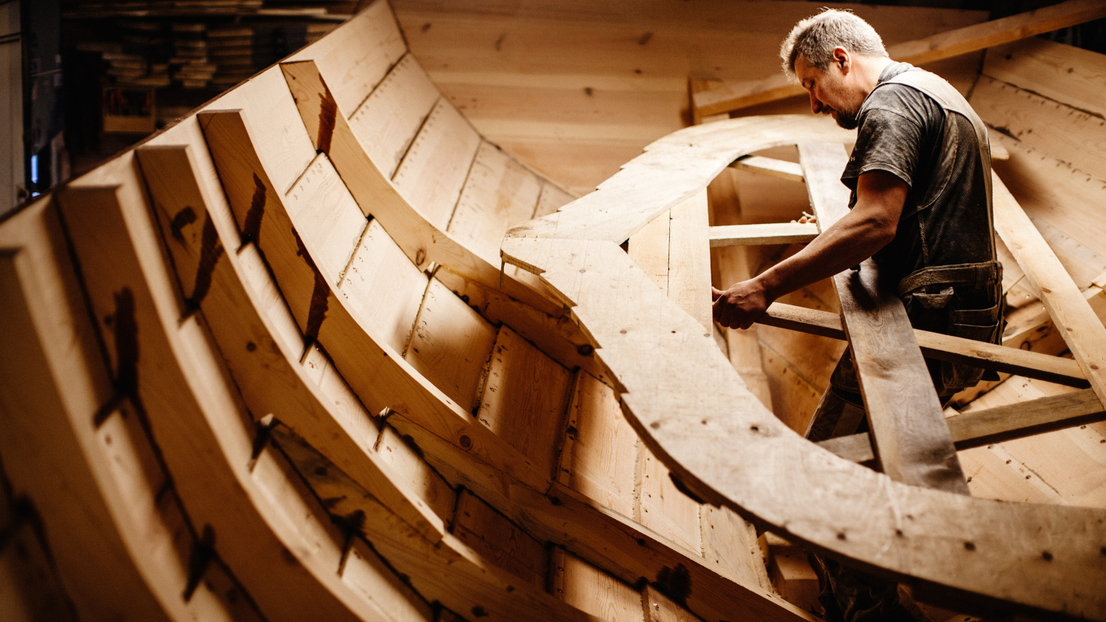 Kuvassa on veneenveistäjä Marko Nikula ja puuveneen runko tekeillä.  