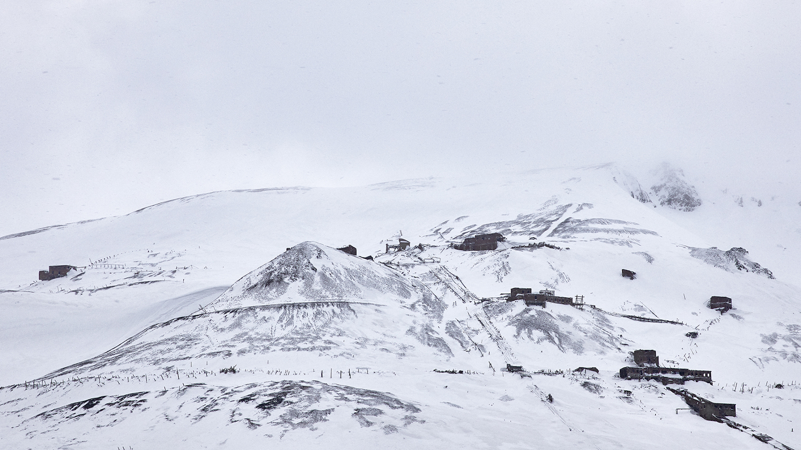 Kuvassa on talvisen Siperian kaivosvuoren rinne.  Kuva on musta-valkoinen.