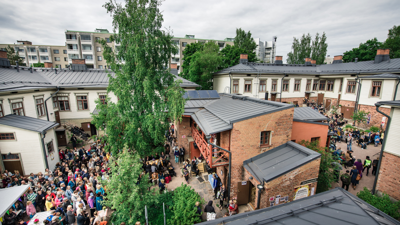 Kuvassa on Annikin runofestivaalia yleisöineen puukorttelissa, jossa on vanhoja puutaloja.  Kuva on otettu yhäältä päin ja yleisö näkyy korttelin keskellä.