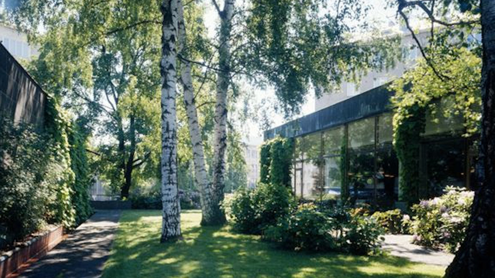Kuvassa on viherpihaa Alvar Aallon suunnittelemasta Kansaneläkelaitoksen päärakennuksesta ja oikealla näkyy lasista julkisivua.