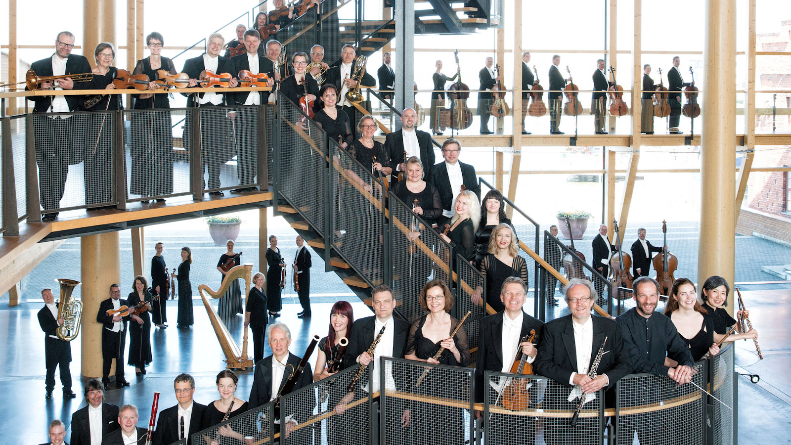 Kuvassa on Lahti Sinfonian orkesterin jäsenet Sibelius-talon portailla risteillen.