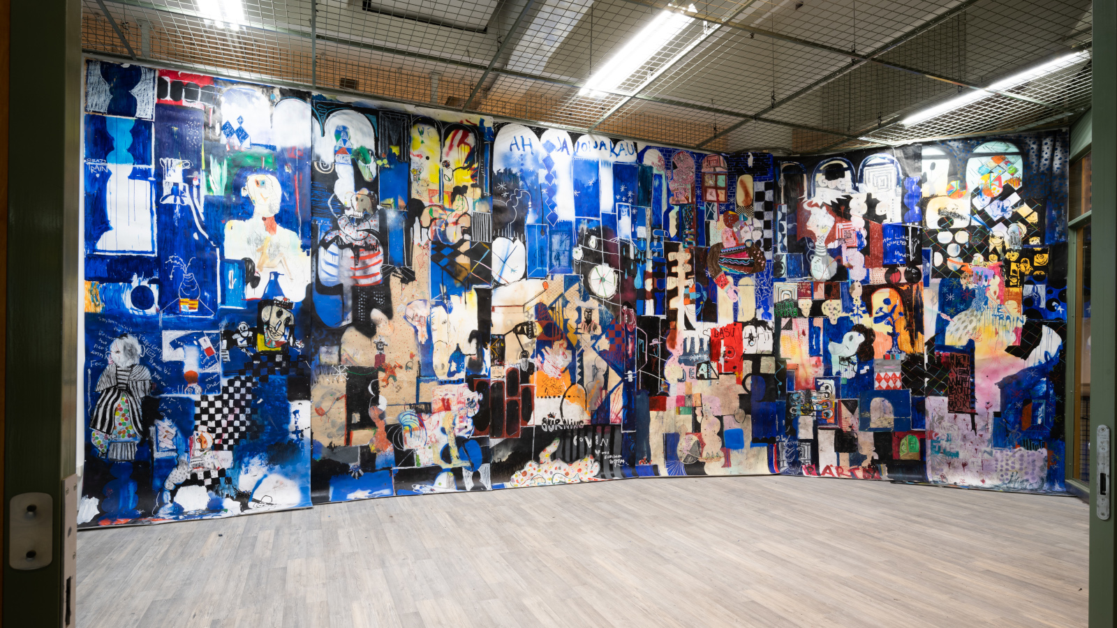 Kuvassa on Kim Somervuoren kuvataidetta iso seinällinen. Kuvasto on kollaasimaista ja sävy sininen.