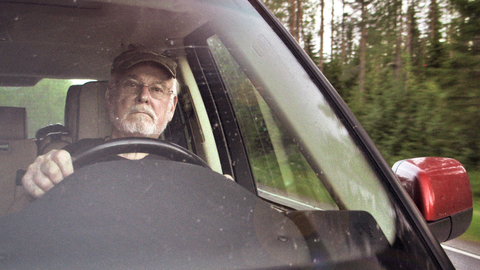 Kuvassa on elokuvasta otettu kuva Hannu Karposta ajamassa autoa.  Kuva on edestä ja tuulilasin takaa näkyy Karpo.