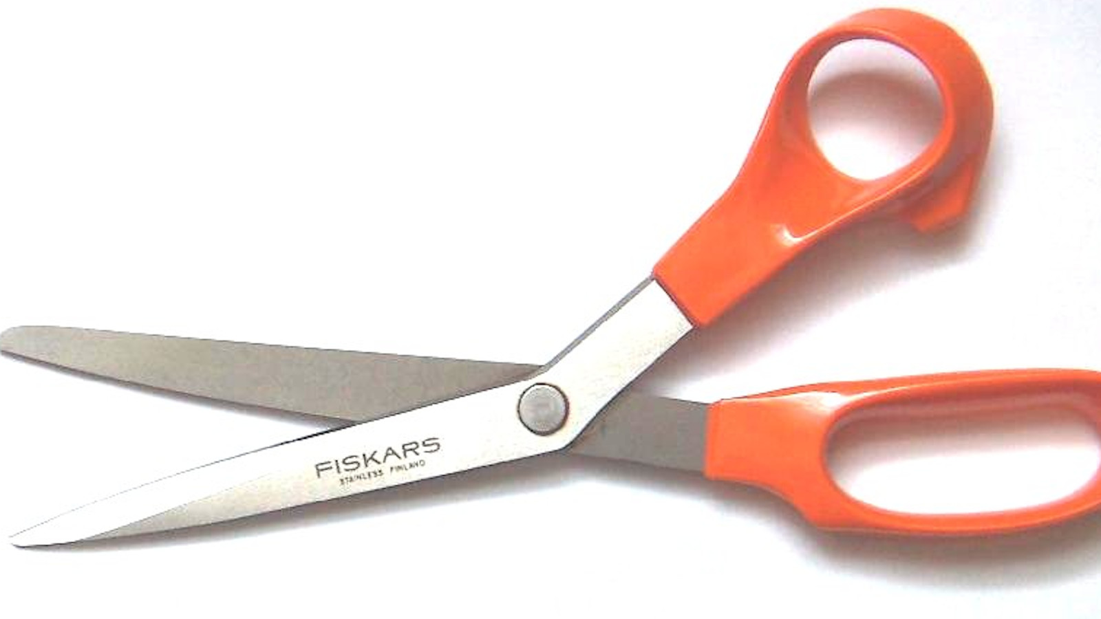 Kuvassa on oranssit Fiskarsin sakset harmaalla alustalla.