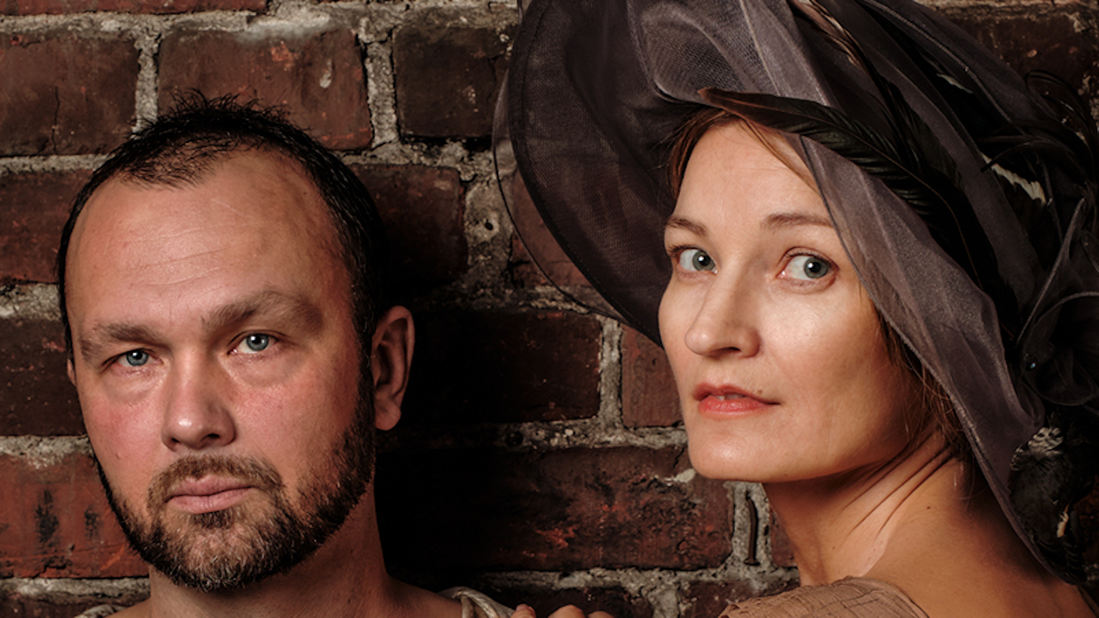 Kuvassa ovat Jari Virman ja Matleena Kuusniemi, jolla on iso musta hattu päässään. Kuva on kasvokuva molemmista.