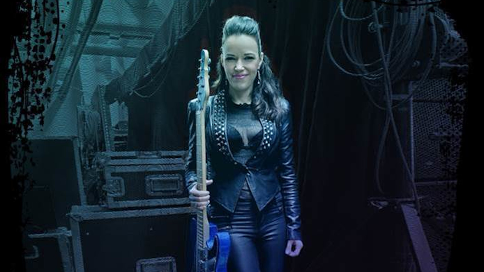 Kuvassa on Erja Lyytinen seisomassa kitara kädessään pystysuorasti.