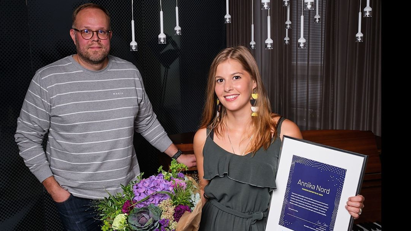 Kuvassa on Annika Nordin kukkasten kanssa ja mieshenkilö, joka jakoi Vuoden raportoija -palkinnon.