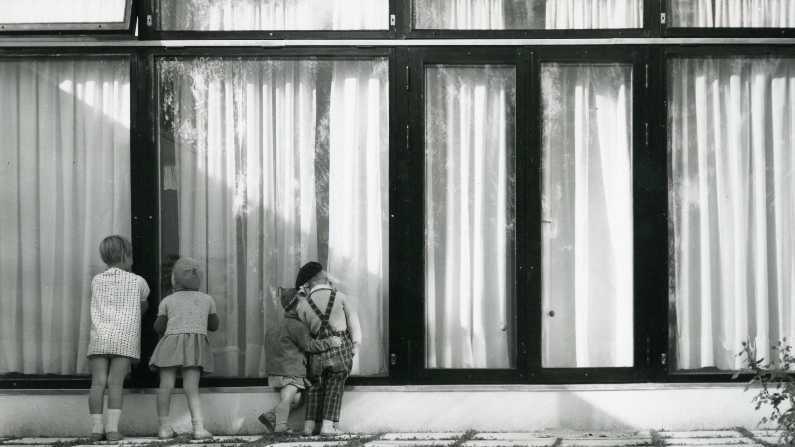 Kuvassa on Otonpesä Tapiolassa ja rakennuksessa on suuret ikkunat.  Lapset kurkkivat ikkunasta.