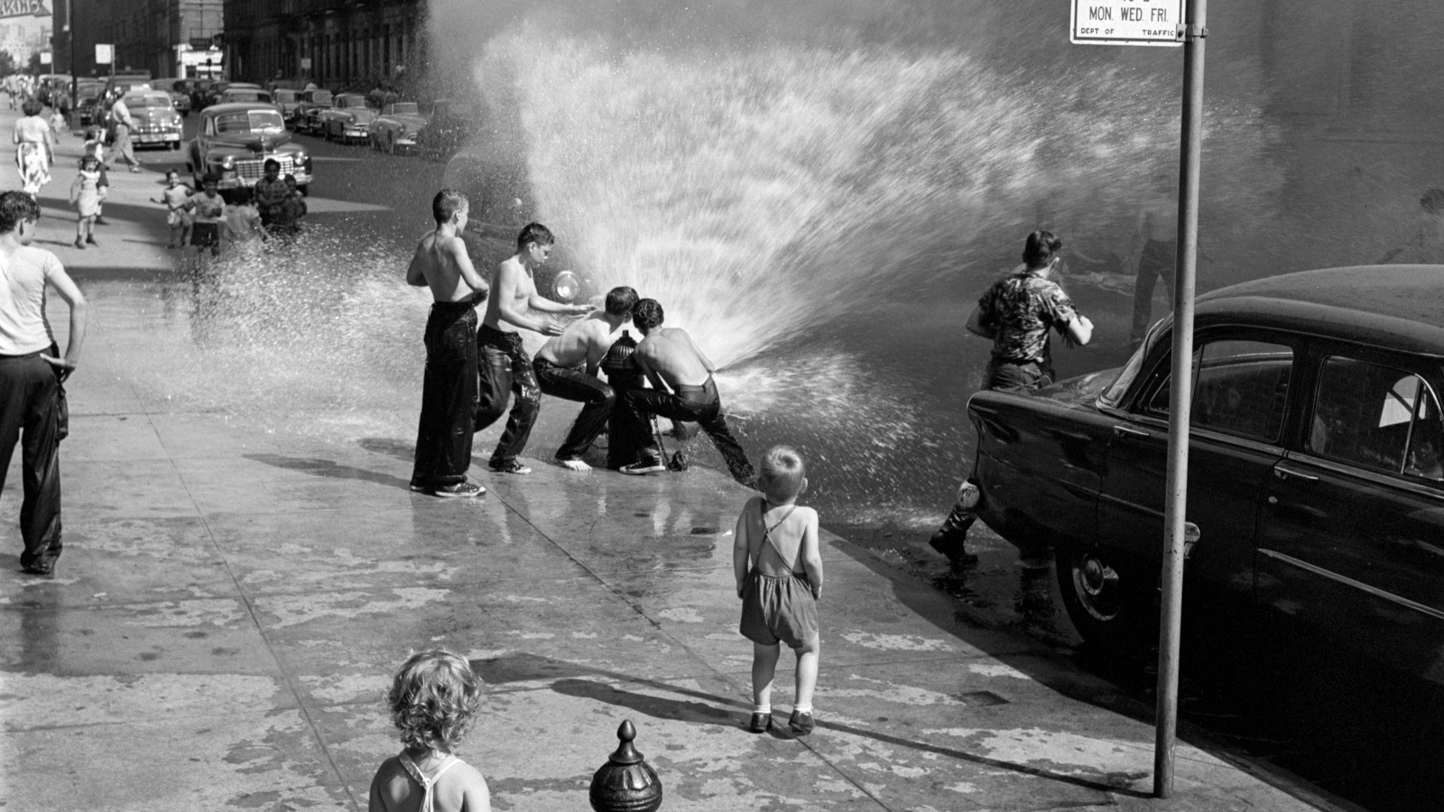 Kuvassa on poikia leikkimässä New Yorkissa kadulla suihkuavalla vesipostilla. 