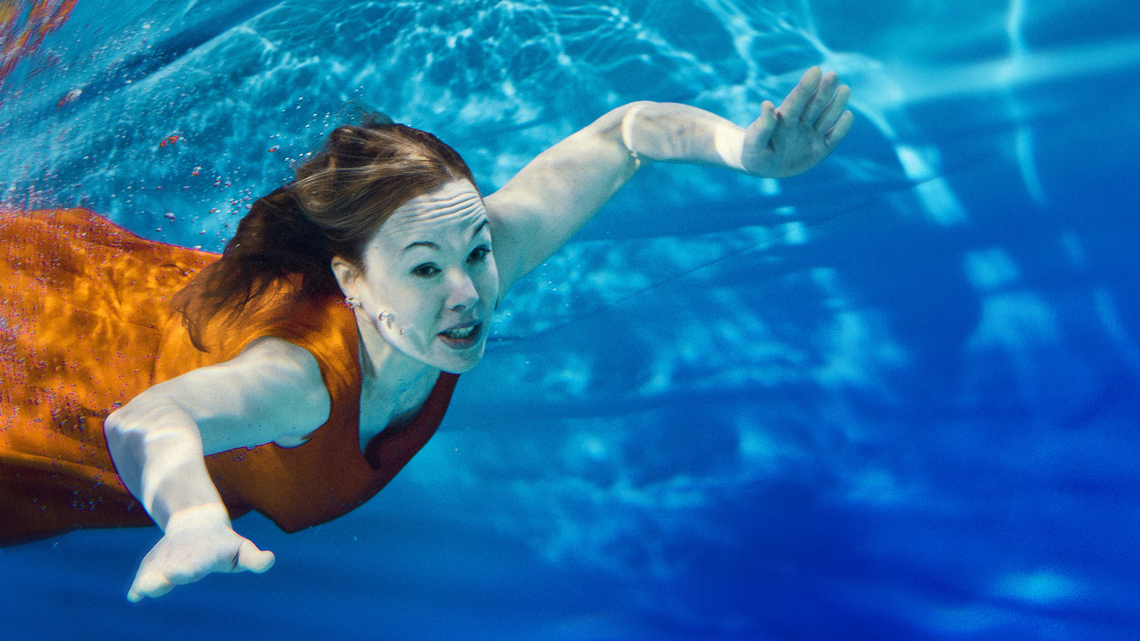 Kuvassa on Anu Pentikiä näyttelevä Helka Periaho uimassa kirkkaan sinisessä vedessä.