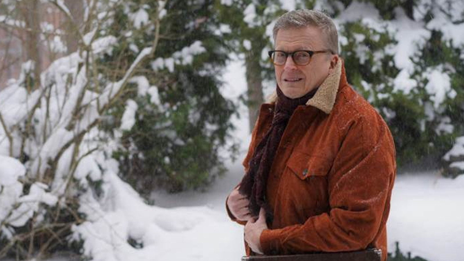 Kuvassa on Mikko Harjunpää tiilen ruskeassa takissa ulkona lumisessa metsässä.