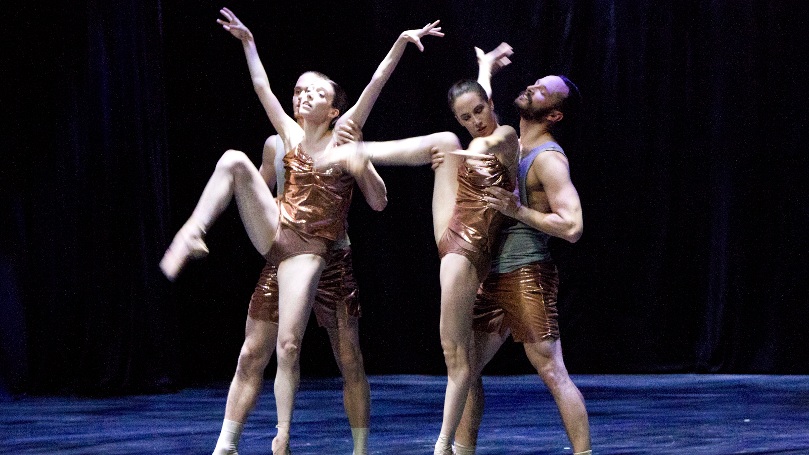 Kuvassa on Dresden Frankfurt Dance Companyn tanssijat pronssin värisissä asuissa, jotka jättävät hihat ja jalat paljaiksi.  Tanssijoissa on kaksi naista ja kaksi miestä.  