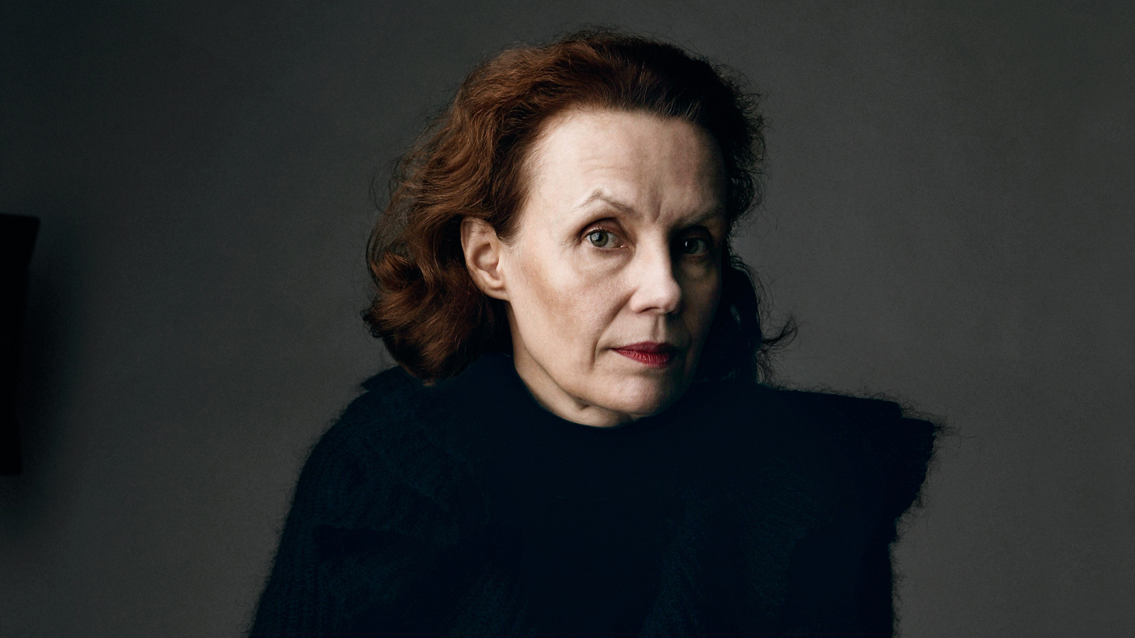 Kuvassa on Kaija Saariaho puolivartalokuvassa tummahkolla taustalla mustassa puserossa.