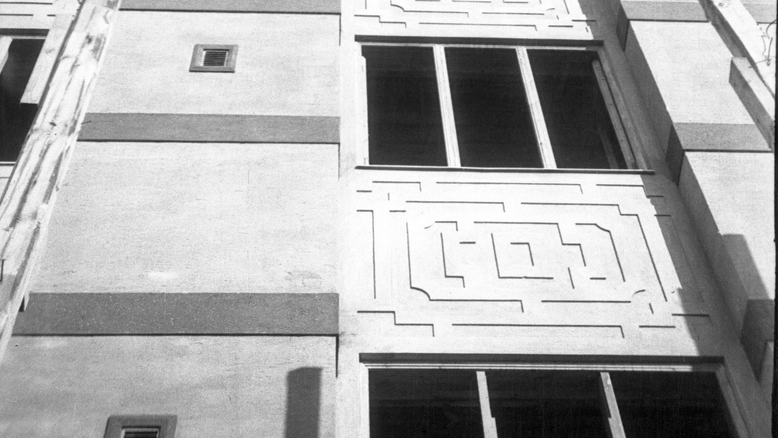 Kuvassa on Viipurin maalaiskunnan talon seinää, jossa näkyy ikkunoita ja betoniin valettu kuvio.