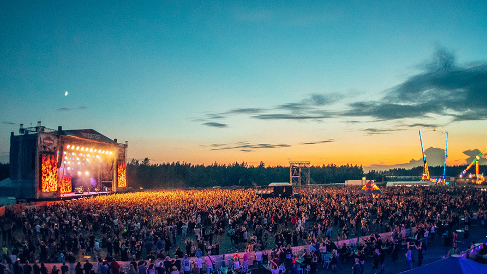 Kuvassa on Rockfestin areena ja yleisö iltavalistuksessa auringon laskiessa.