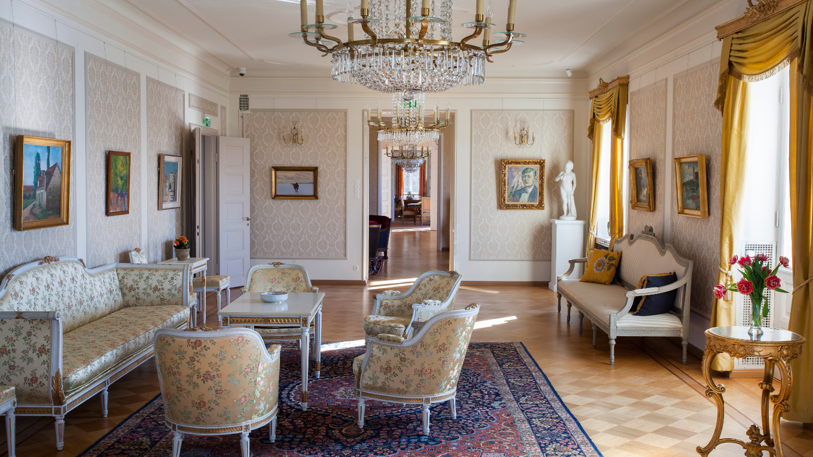 Kuvassa on Söderlångvikin kalustettu huone, jossa on vanhoja tyylikalusteita ja melko vaaleat värit.  Verhot ovat kullankeltaiset.