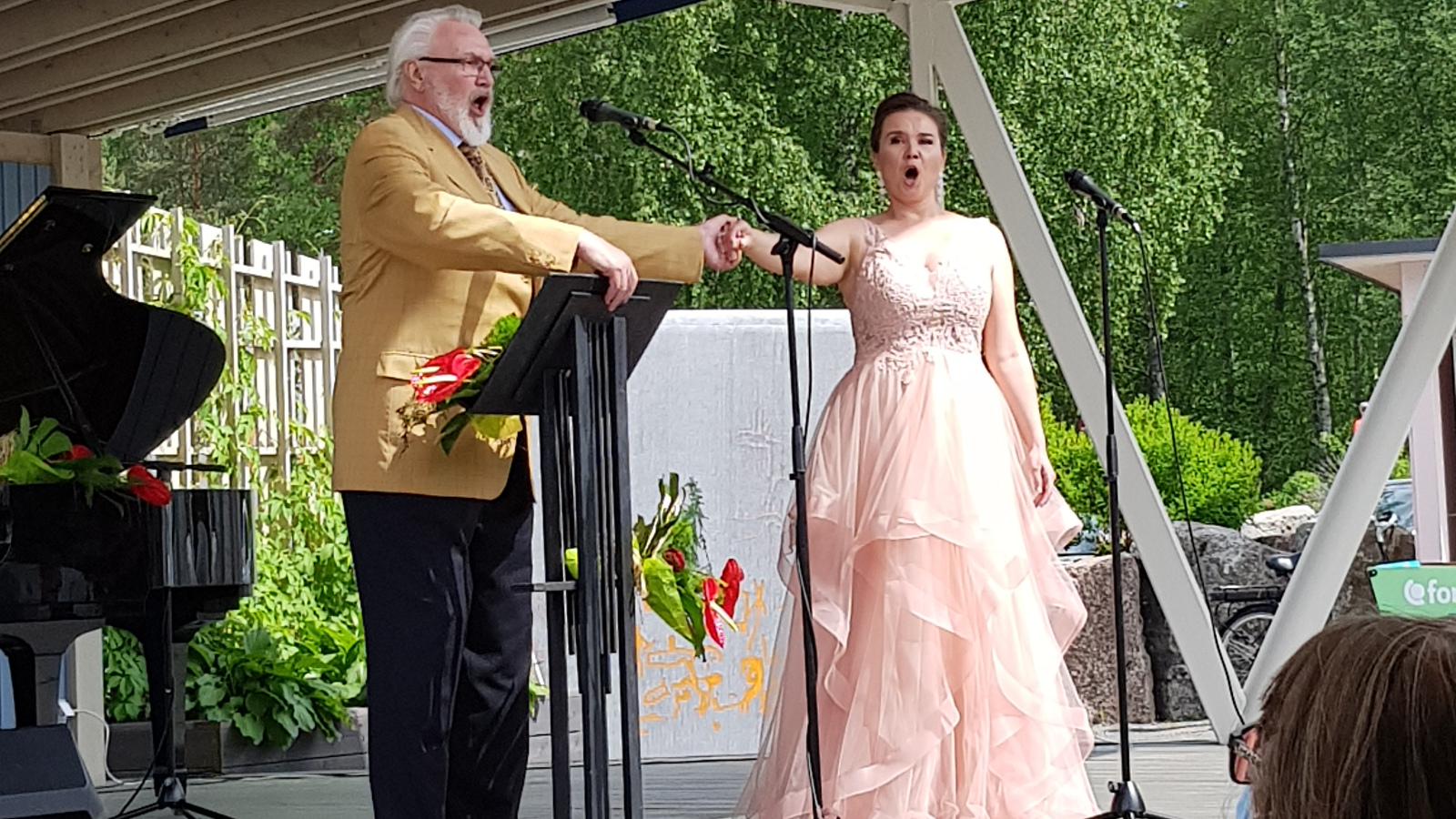 Kuvassa ovat laulamassa Jaakko Ryhänen ja Hannakaisa Nyrönen vaaleanpunaisessa puvussa.