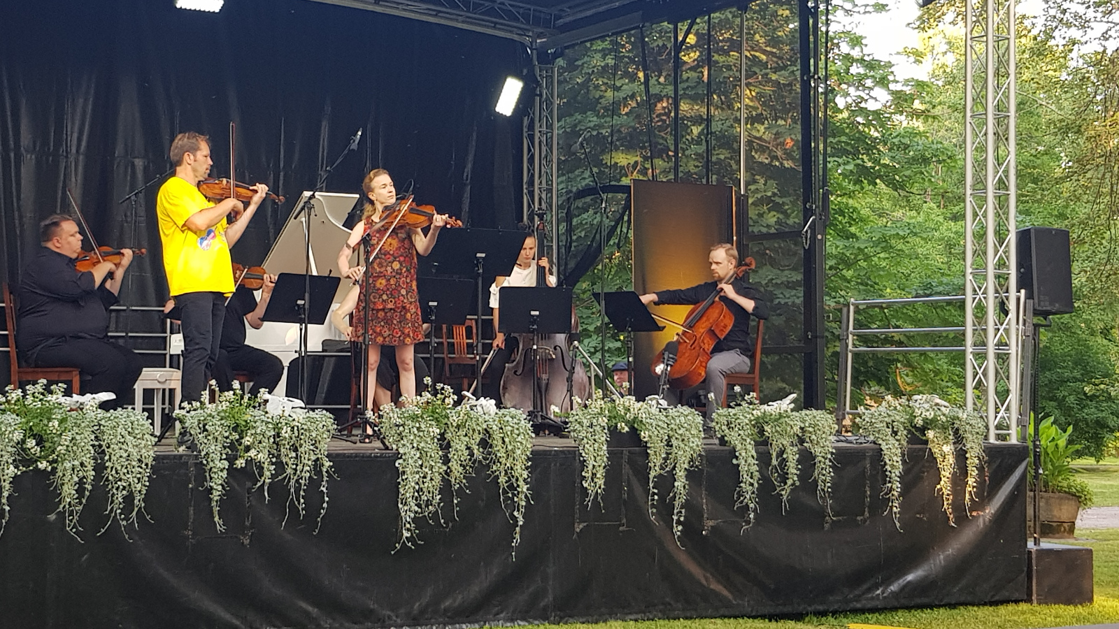 Kuvassa on Finnkampen konsertin soittajia ja keskellä Jukka Merjanen viuluineen ja Kirsikka de Leval Jezierski alttoviuluineen.  Taustalla muut soittajat näyttämöllä.