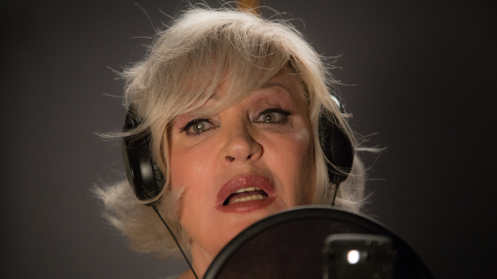 Kuvassa on Hannele Laurin kasvot kuulokkeet päässä laulamassa.
