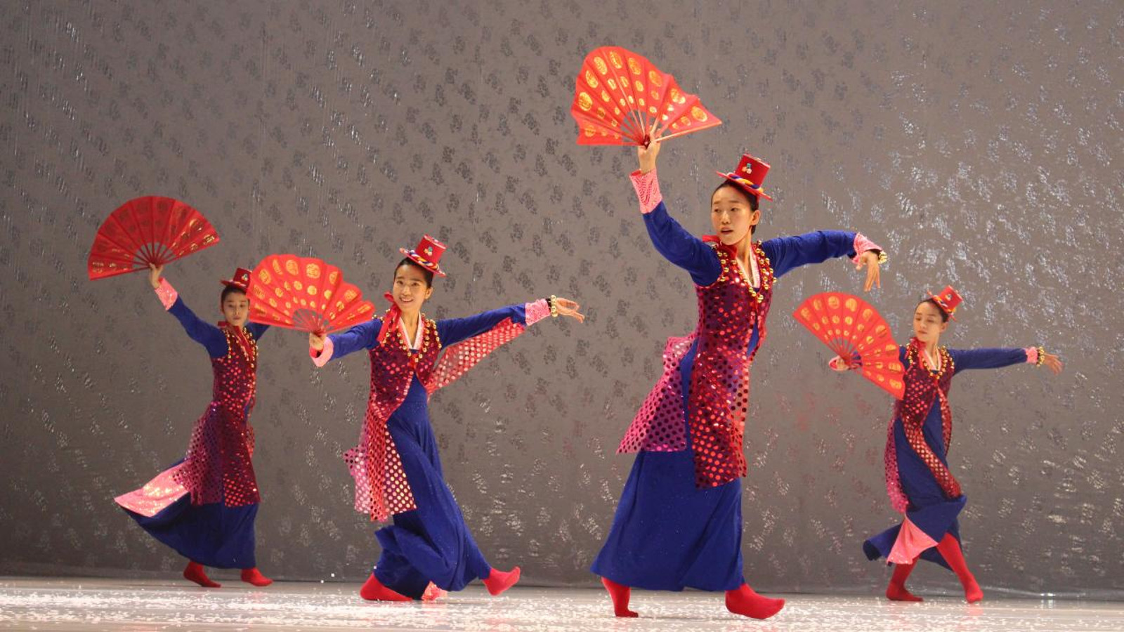 Kuvassa on tanssijoita traditionaalisiin pitkiin koristeltuihin pukuihin ja viuhkat kädessään. Värit ovat sinisiä ja punaisia.
