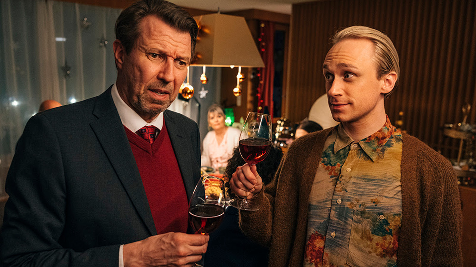Kuvassa ovat Martti Suosalo ja Christoffer Strandberg puolivartalokuvassa seisomassa ravintolassa viinilasit kädessään.
