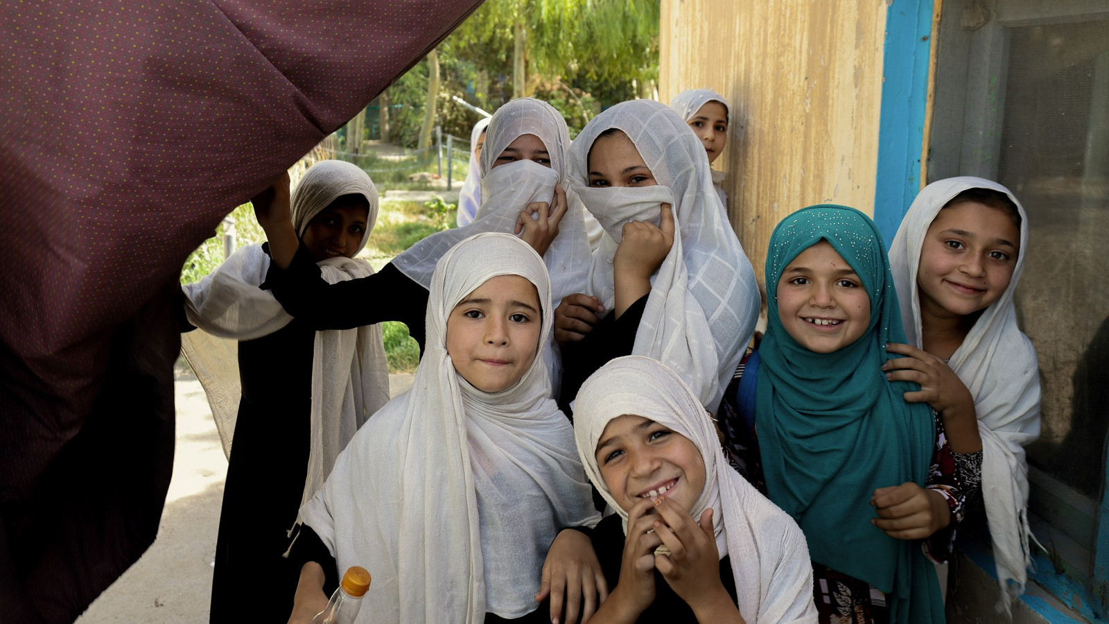 Kuvassa on kahdeksan tyttöä Afganista ja heillä on valkoiset huivit päässään.  Tyttöjen ilmeet ovat iloisia.