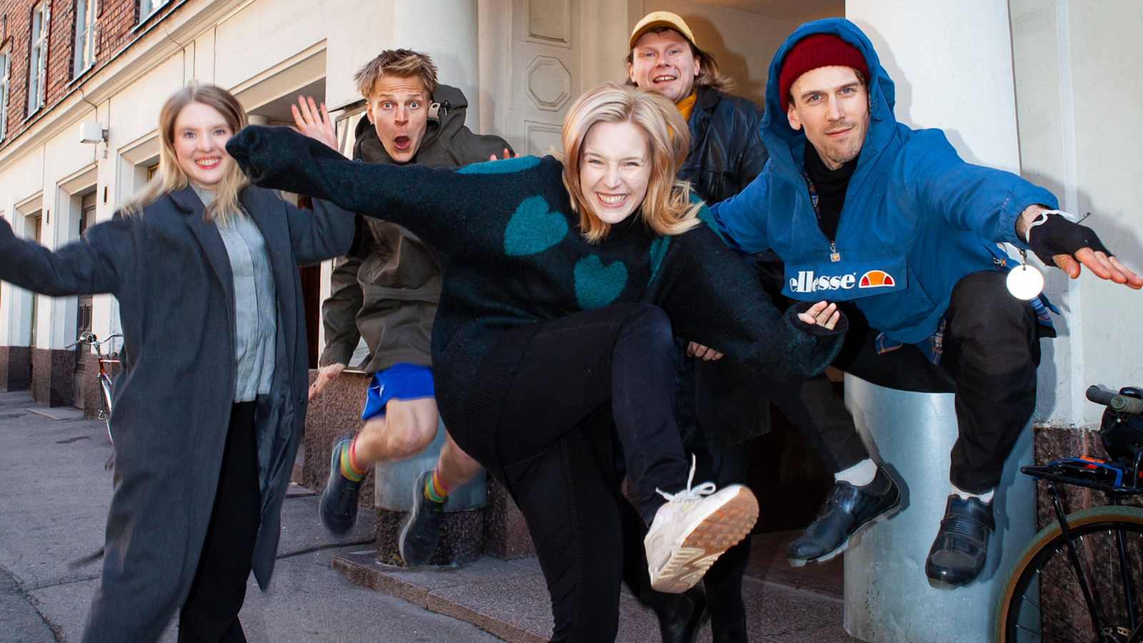 Kuvassa on neljä näyttelijää hypänneenä ilmaan ja etu oikealla on Juho Mantere kadulla Helsingissä.