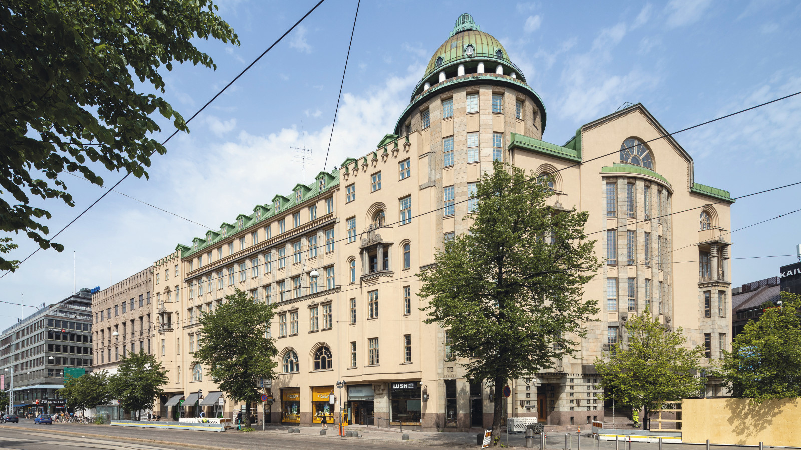 Kuvassa on Uusi ylioppilastalo Helsingissä. Talo on kellertävä 5-kerroksinen ja siinä on torni kulmassa. 