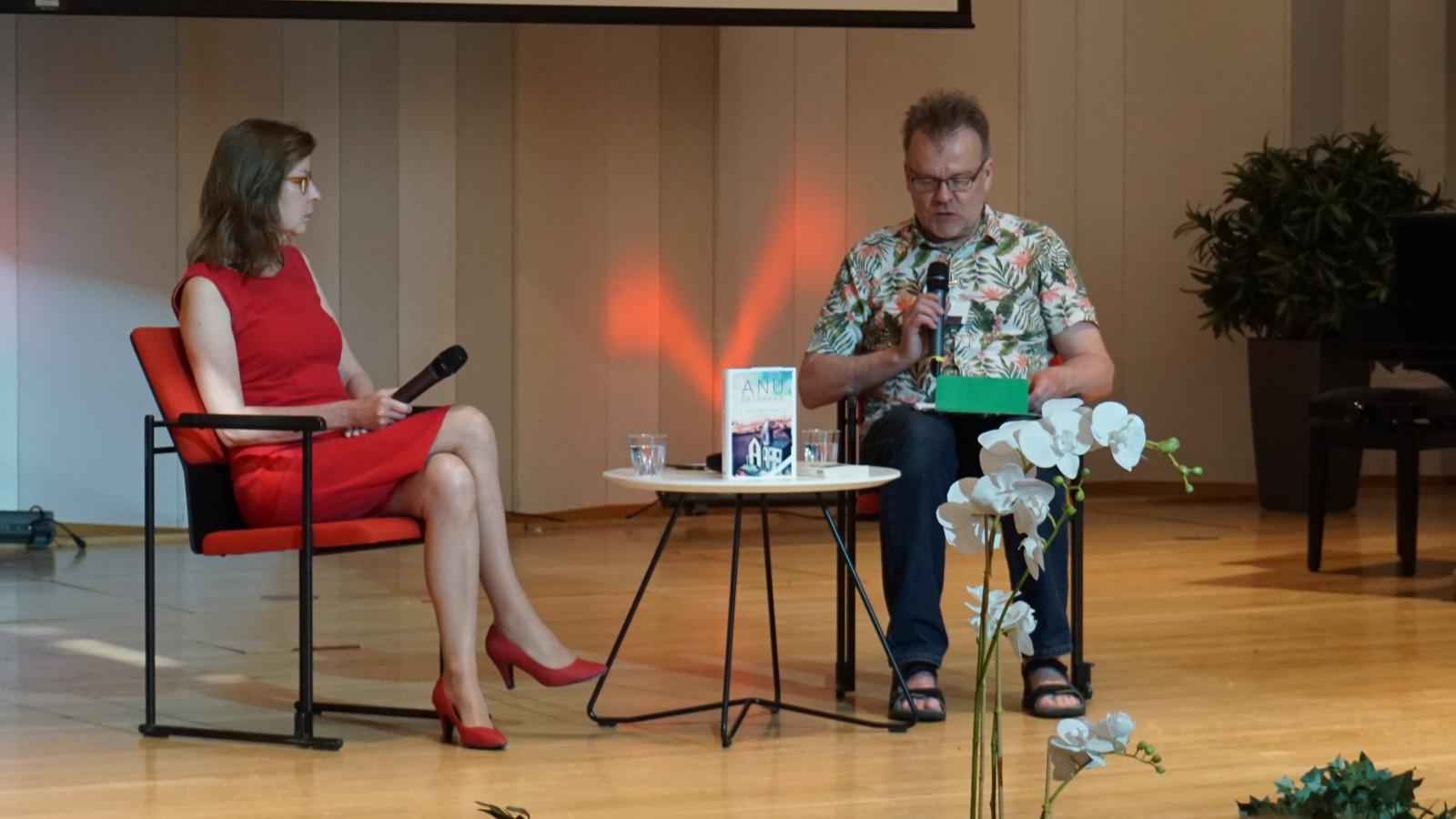 Kuvassa on Anu Patrakka punaisessa puvussa haastateltana ja haastattelijana Pasi Luuhtaniemi kirjavassa paidassa.