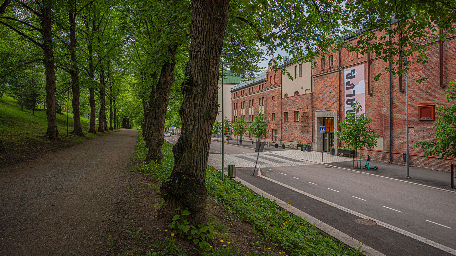 Kuvassa on punatiilinen Malskin rakennus ja katua, jossa on vihreitä puita.