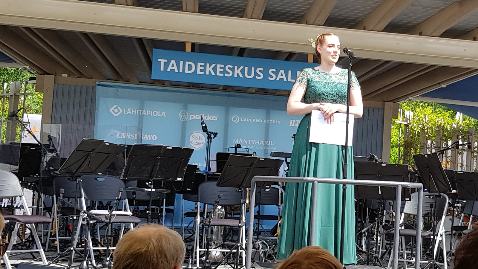 Kuvassa on Kaisamaisa Erämies kiittämässä stipendistään ja hänellä on vihreä pitkä mekko päällään.