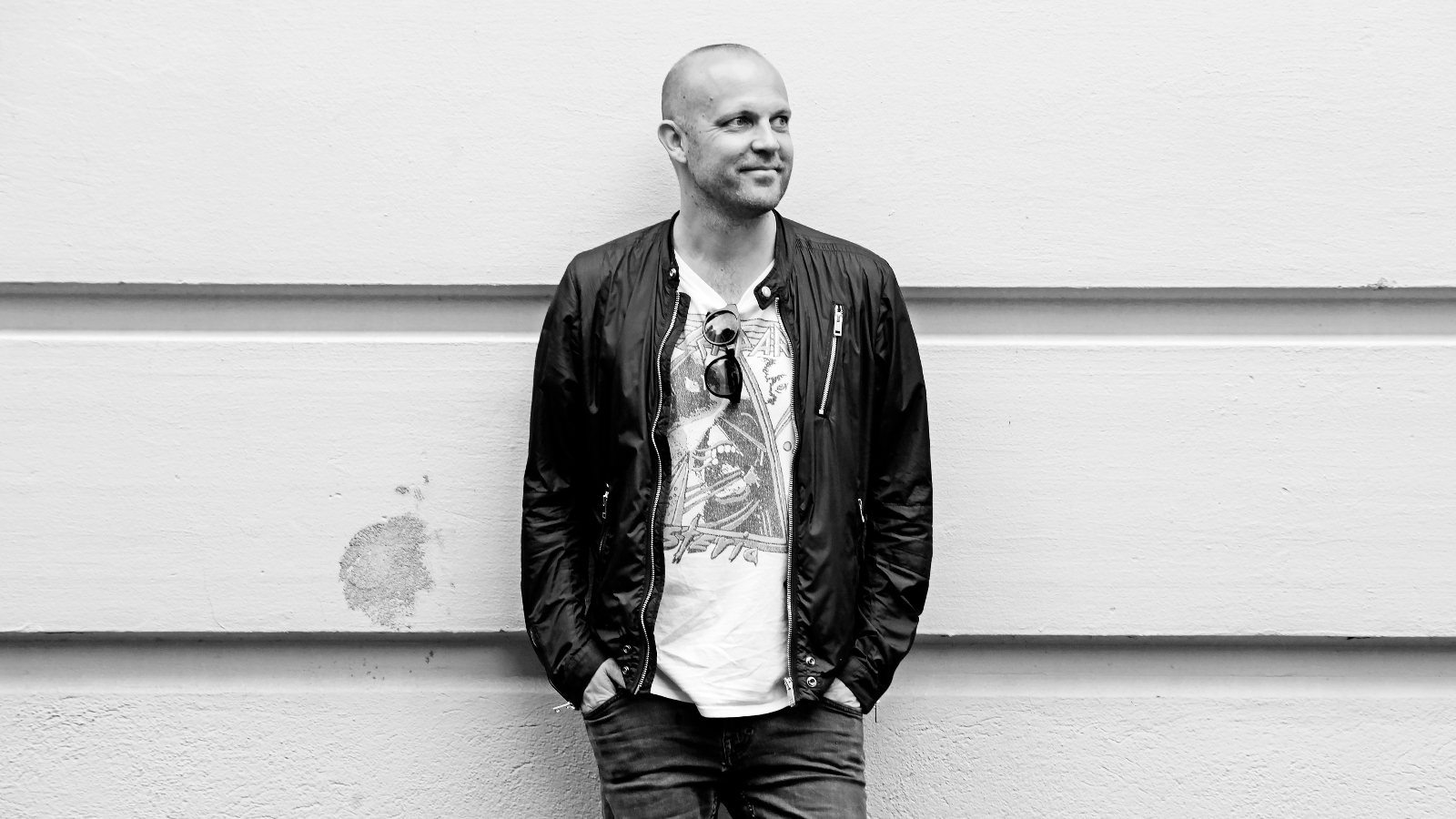 Kuvassa on Mikko Kosonen mustassa nahkatakissa ja vaaleassa t-paidassa. Kuva on puolivartalokuva ja musta-valkoinen.