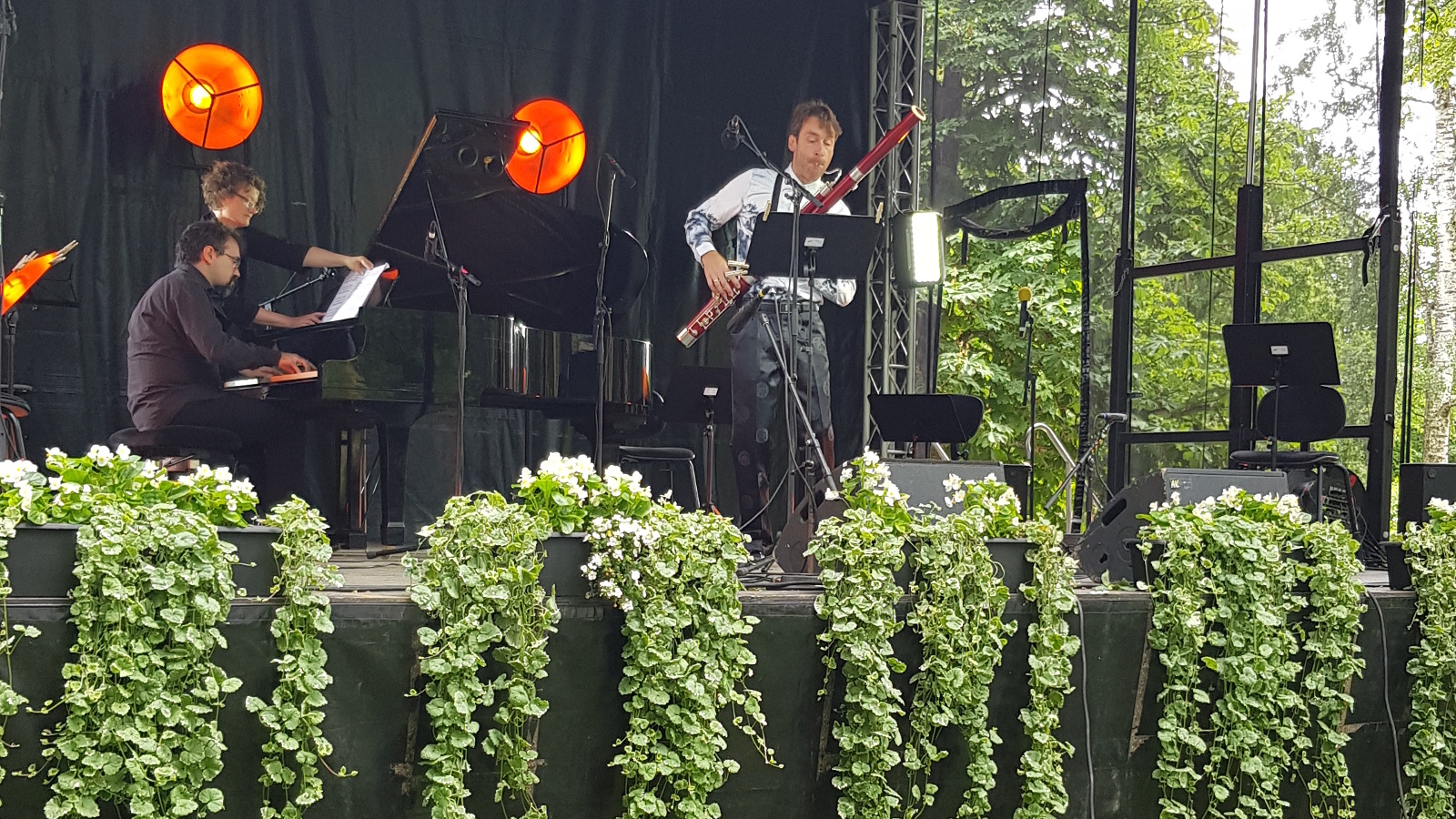 Kuvassa ovat Bence Bogányi soittamassa fagottia ja vasemmalla Tuomas Turriago soittamassa flyygeliä. He ovat puistonäyttämöllä.