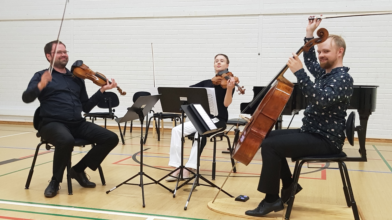 Kuvassa ovat Petteri Iivonen, viulu, Kirsikka Leval de Jezierski, alttoviulu ja Lauri Kankkunen, sello, lopettamassa konserttia rokat ylhäällä. 