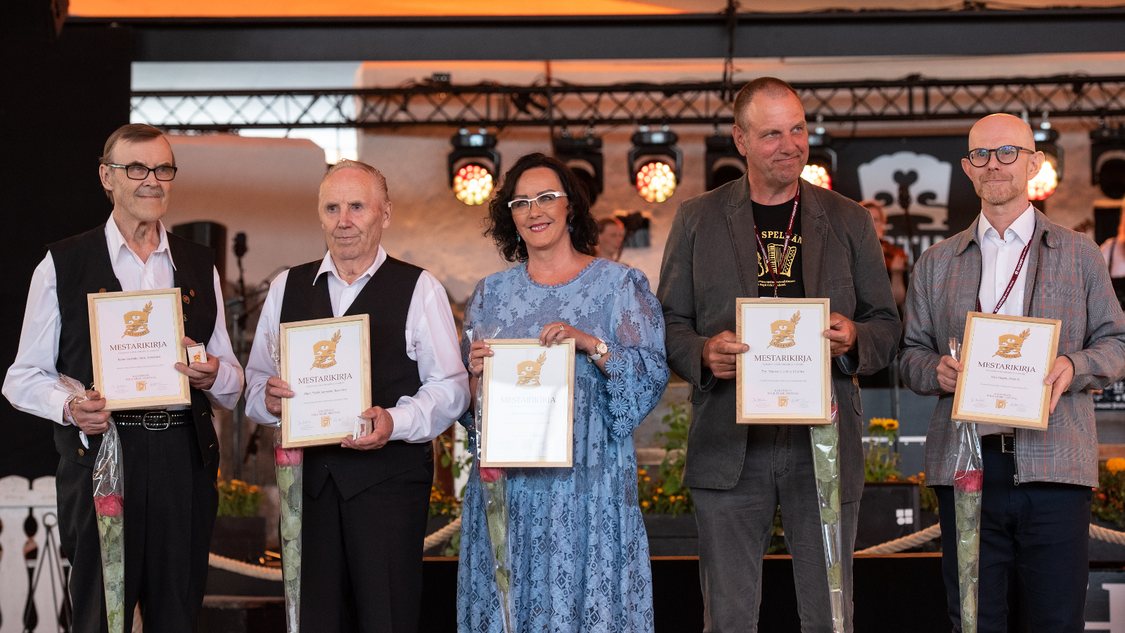 Kuvassa ovat mestaripelimannit Reino Reino Uusitalo, Tore Johansson, Raila Järvelä, Matti Peltola ja Petri Hoppu kunniakirjat käsissään. 