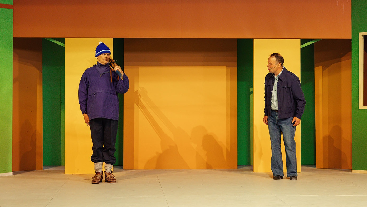 Kuvassa on kaksi miestä, jotka seisovat molemmilla puolilla leveää ovea.