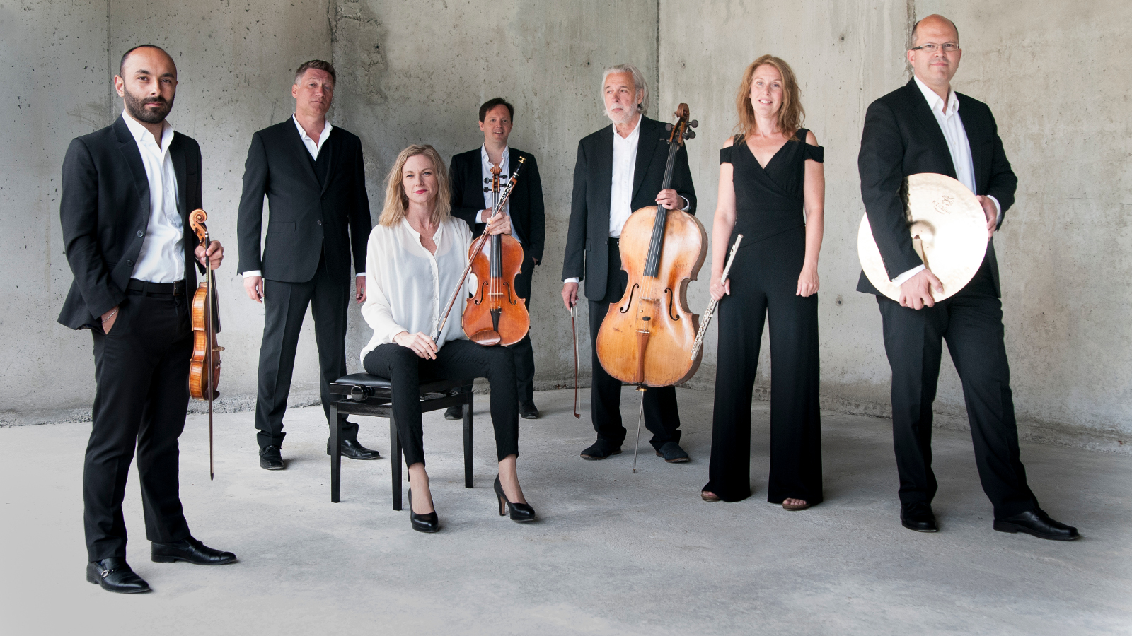 Kuvassa ovat Norrbotten NEO:n soittajat, joista kuusi seisoo soittimet kädessään ja yksi istuu.