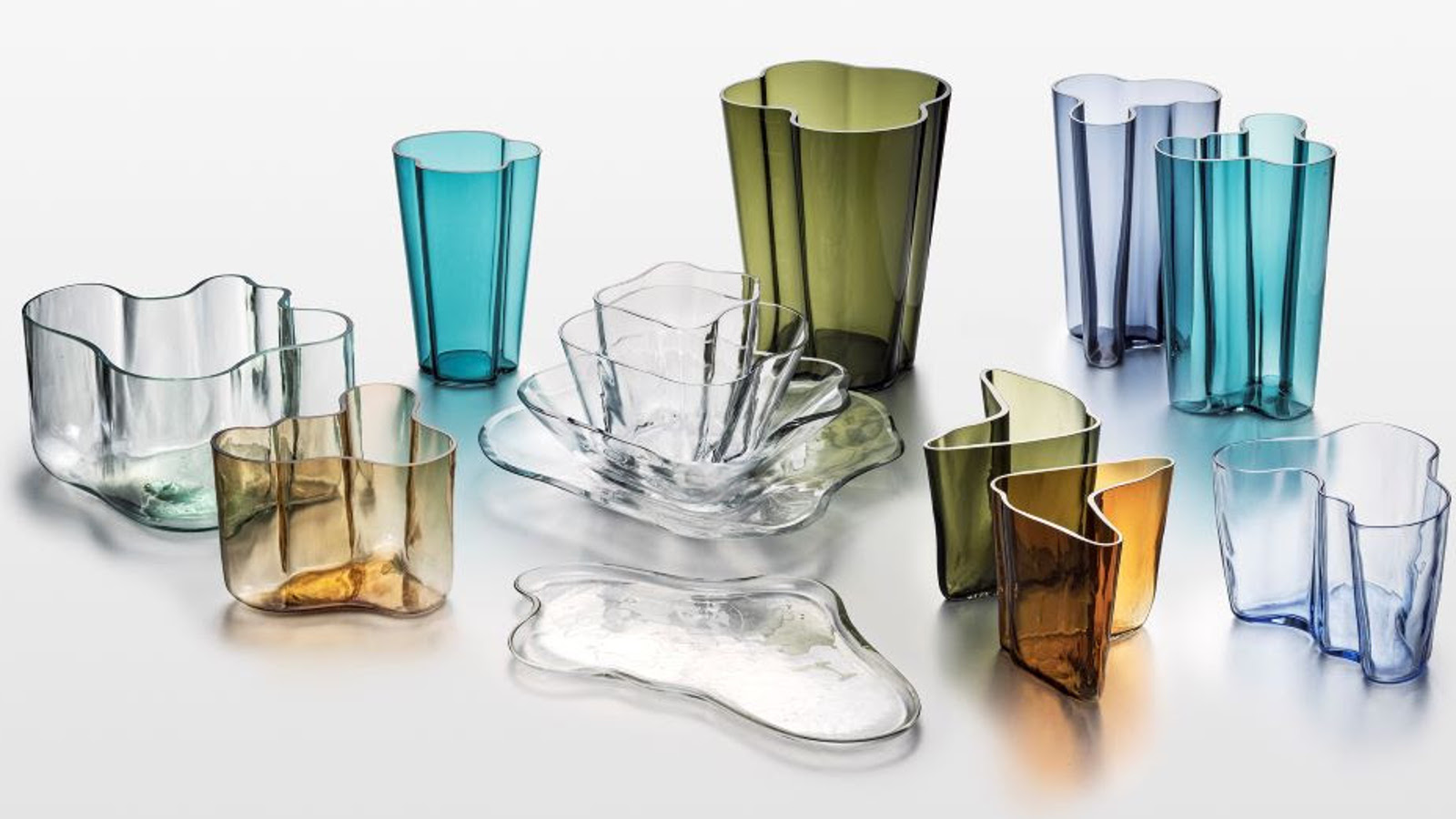 Kuvassa on  Iittalan Alvar Aalto -kokoelman erivärisiä lasiesineitä kuten maljakoita ja maljoja.